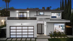 Et moderne hus med to etager, garage, store vinduer og en velplejet græsplæne.