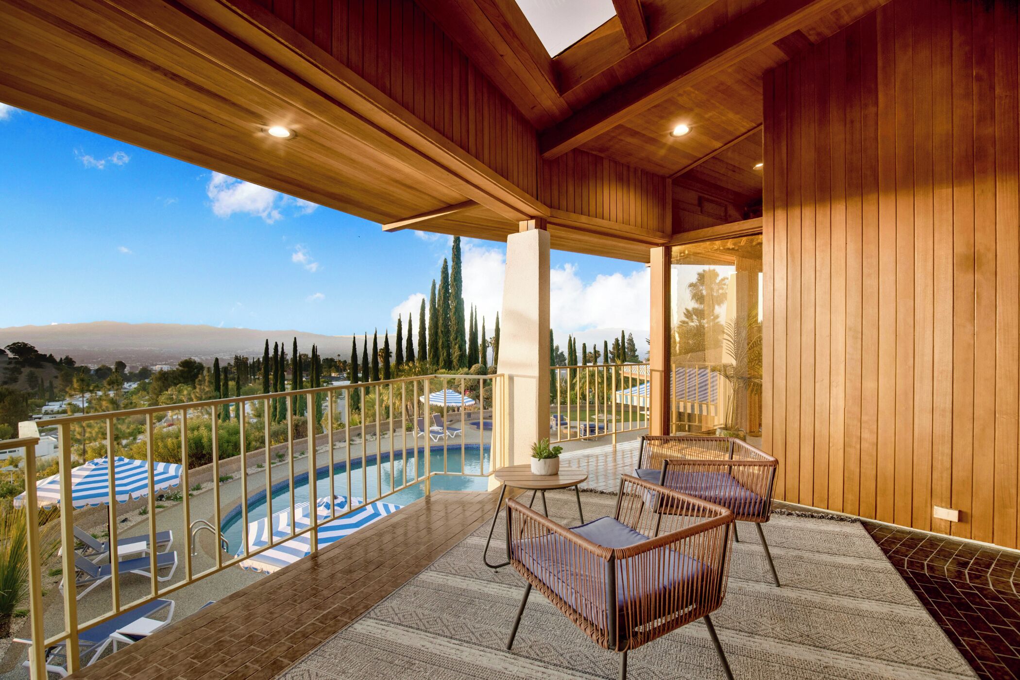 Un balcone in legno con piscina, sedie a sdraio e vista sul paesaggio.