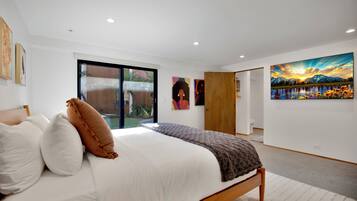A bedroom with a bed, a large window, and artwork on the walls.