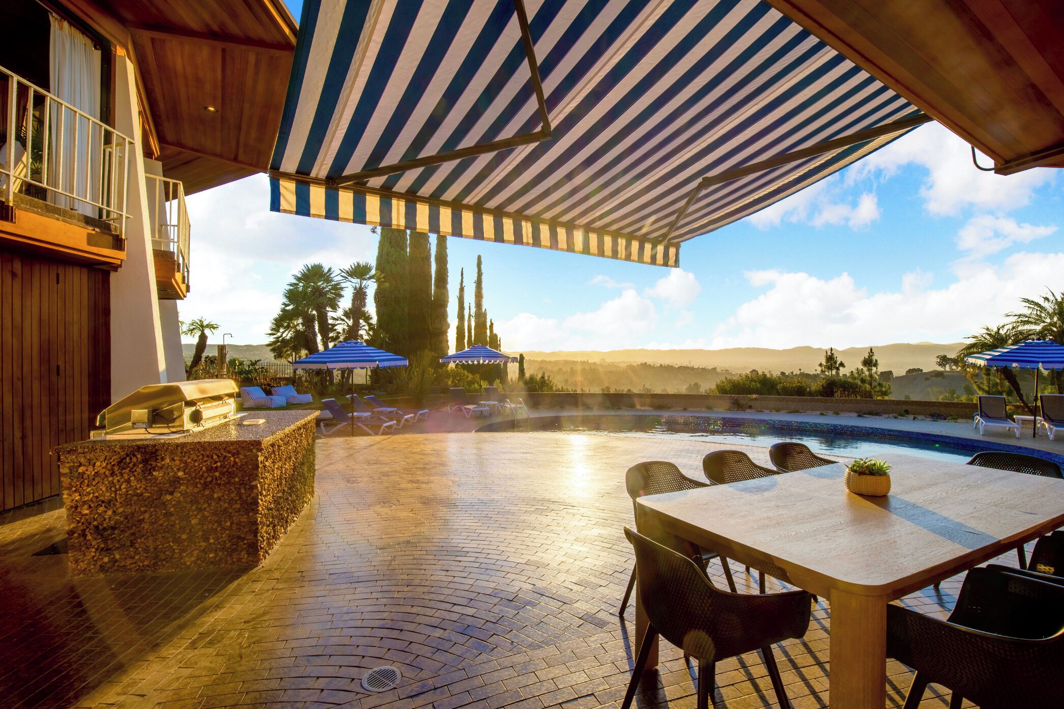 An outdoor patio with a pool, lounge chairs, and umbrellas.