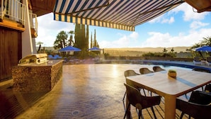 Un patio al aire libre con piscina, sillas de descanso y sombrillas.