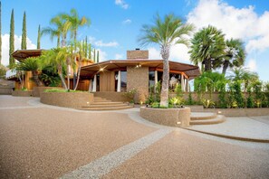 A modern house with a stone facade, a wooden deck, and a landscaped garden with palm trees. - Via Vallarta (Encino)