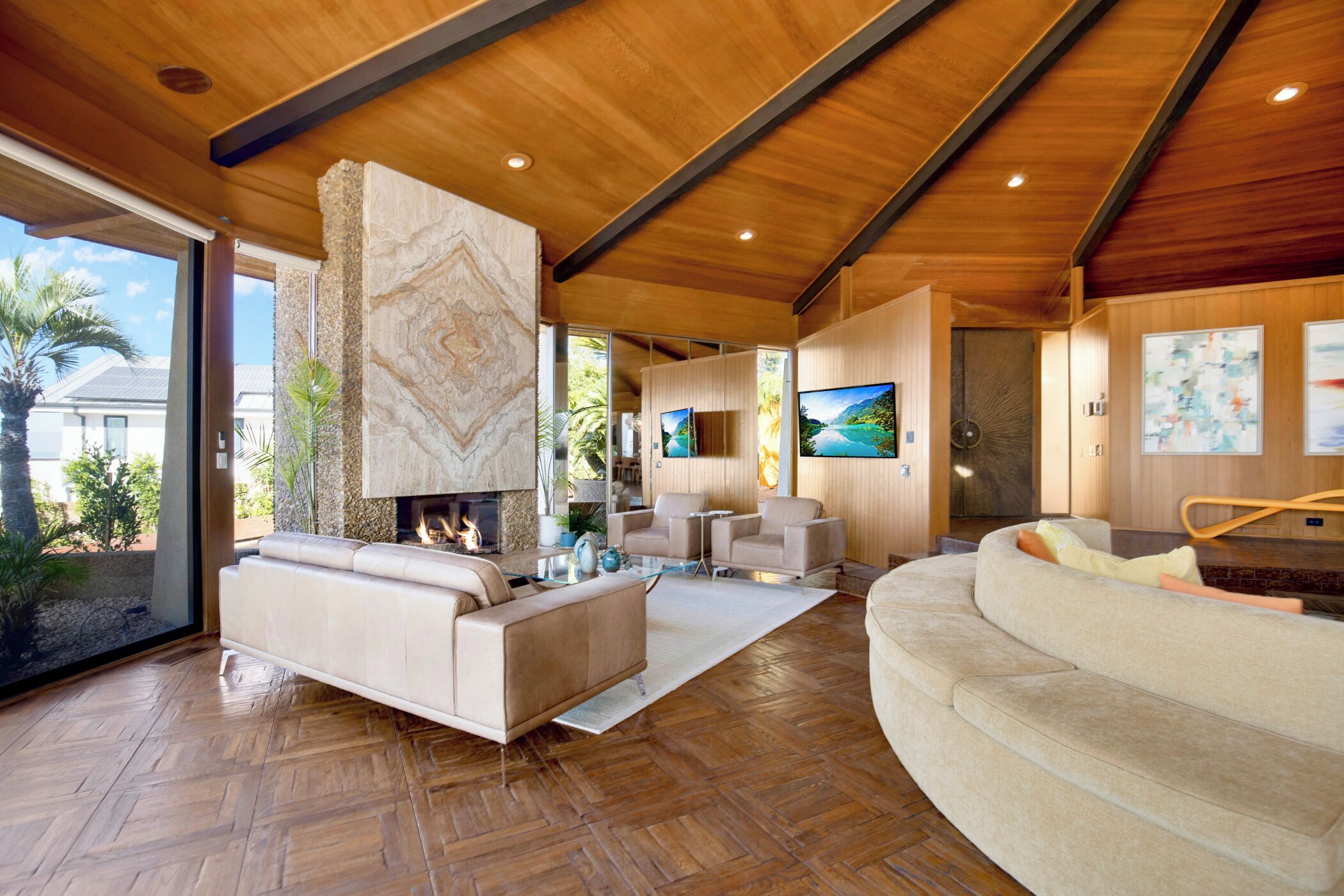 A spacious living room with a fireplace, comfortable seating, and a large TV.