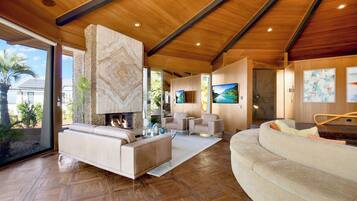 A spacious living room with a fireplace, comfortable seating, and a large TV.