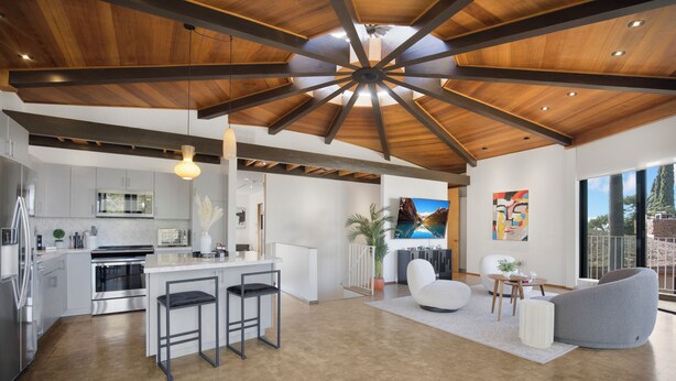 Una cocina moderna con electrodomésticos de acero inoxidable, una isla central con taburetes y un comedor con un amplio ventanal.