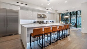 Cozinha moderna com uma ilha grande, eletrodomésticos de aço inoxidável e um espaço de estar com banquetas.
