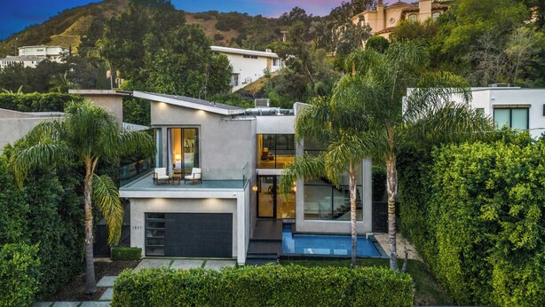 Uma casa moderna de dois andares com telhado plano, grandes janelas e uma piscina.