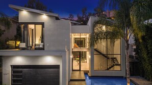 Uma casa moderna de dois andares com garagem, escadaria e piscina.