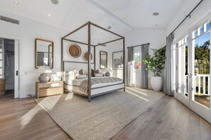 Ein geräumiges Schlafzimmer mit Himmelbett, großen Fenstern und Blick auf Grün.