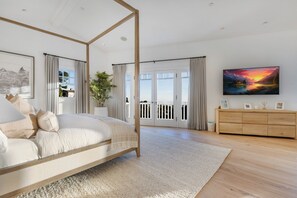 A modern bedroom with a four-poster bed, a wooden dresser, and a large painting on the wall. - Stradella Hideaway (Los Angeles)