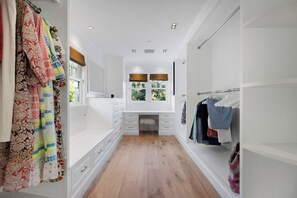 A narrow hallway with a wooden floor, white walls, and a window with blinds. - Stradella Hideaway (Los Angeles)