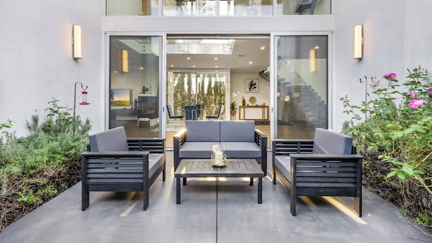 Un espace extérieur aménagé avec deux canapés et une table, entouré de portes vitrées donnant accès à un espace intérieur.