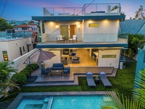 Uma casa moderna de dois andares com um pátio, área de estar externa e piscina.