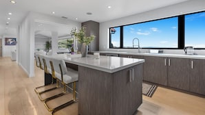 Cozinha moderna com uma ilha grande, banquetas e vista para o exterior.