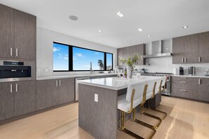 A modern kitchen with a large island, stainless steel appliances, and a view of the sky.
