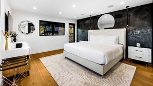 Une chambre moderne avec un grand lit, une table de chevet, un miroir et une vue sur l’extérieur.
