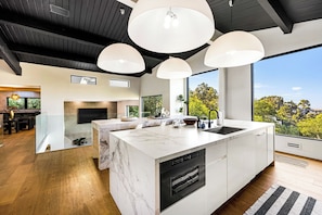 Cozinha moderna com ilha grande, eletrodomésticos embutidos e vista para o exterior.