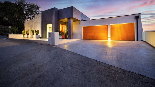 Un bâtiment moderne doté d’une porte de garage, d’une allée et d’une rangée de cactus.