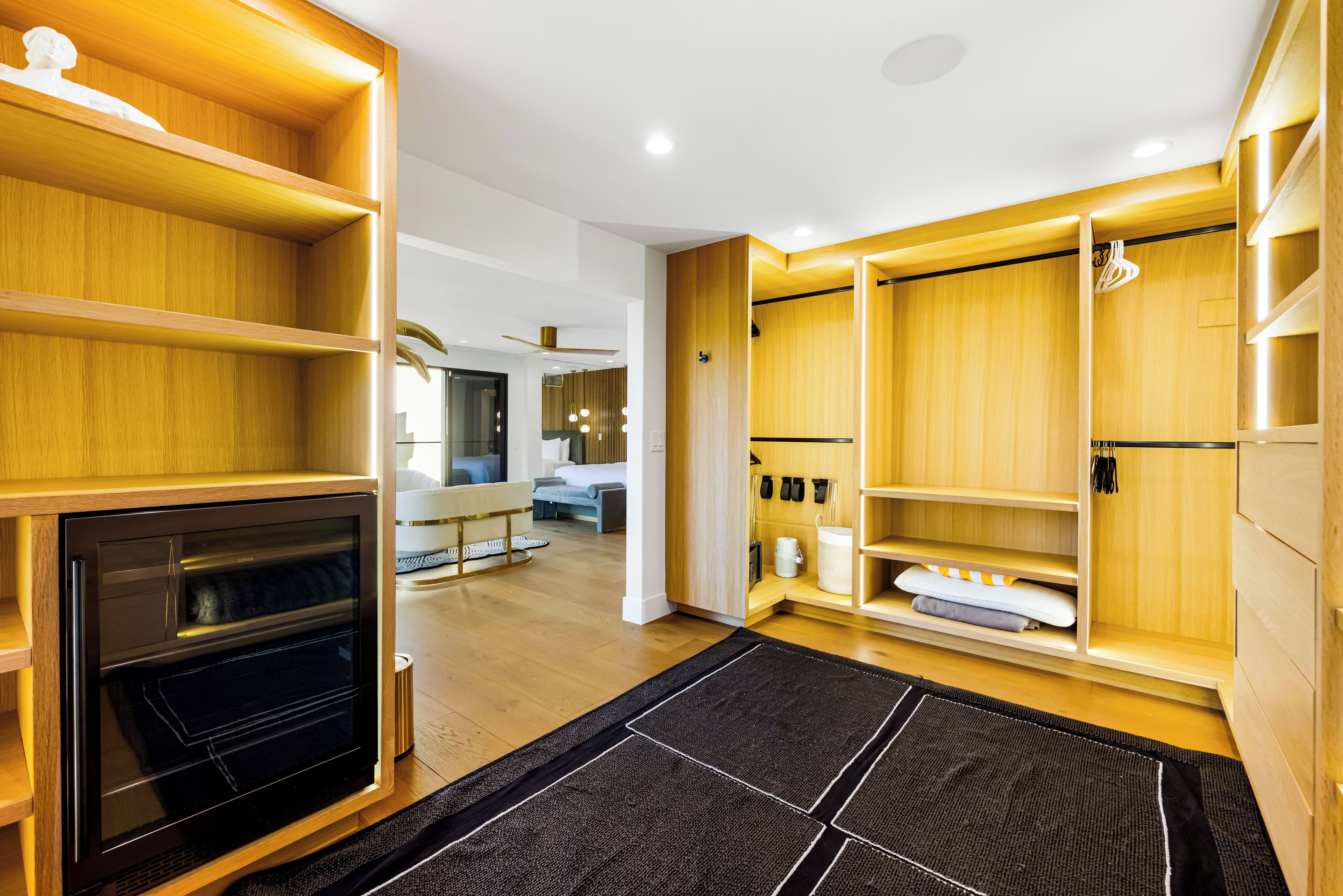 A modern interior with built-in wooden shelving, a built-in oven, and a black and white patterned rug.