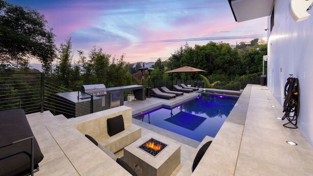 A backyard with a swimming pool, a barbecue grill, lounge chairs, and a fire pit. - Caverna Estate (Los Angeles)