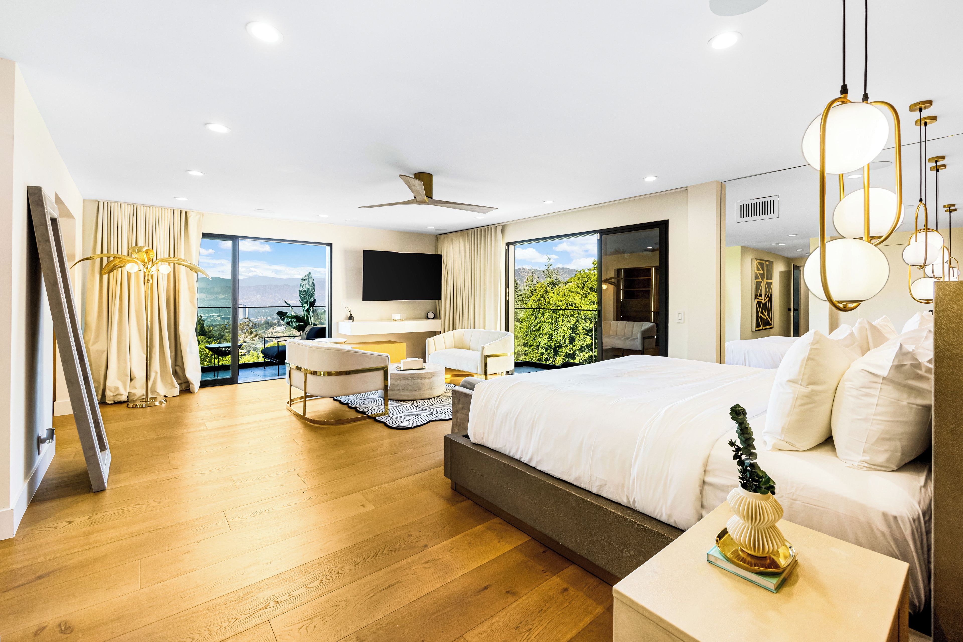 A modern hotel room with a large bed, a desk, a chair, and a view of the outdoors.