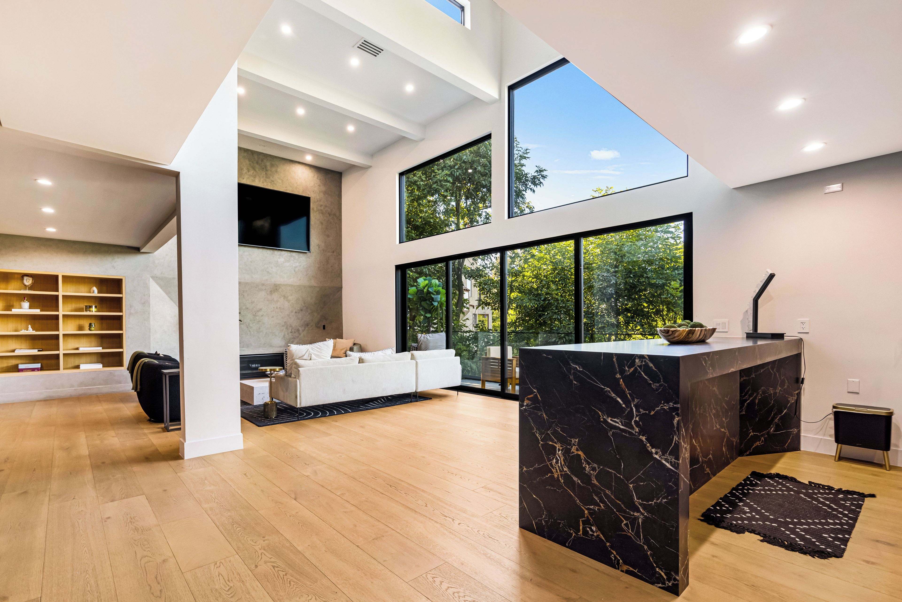 A spacious living area with a large window, a fireplace, and a modern kitchen with a marble countertop.