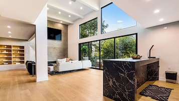 Amplia sala de estar con un ventanal grande, chimenea y cocina moderna con encimera de mármol.