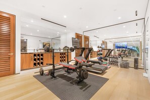 A gym with exercise equipment, wooden cabinets, and a large mirror. - Sierra Mar (West Hollywood)