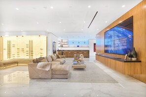 Un moderno vestíbulo de hotel con sofá, mesa de centro y una gran pantalla de televisión.