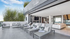 Un área exterior moderna para disfrutar, con varias opciones de asiento, incluyendo sofás y sillones de relax, dispuestas en un amplio patio.