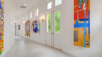Um corredor com paredes brancas, várias portas e obras de arte nas paredes.