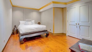 A bedroom with a bed, wooden flooring, white walls, and a wardrobe. - Carolwood Estate (Beverly Hills)