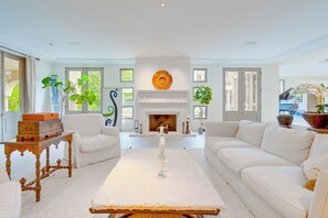 Ein modernes Wohnzimmer mit weißen Sofas, einem Kamin und Zierpflanzen.