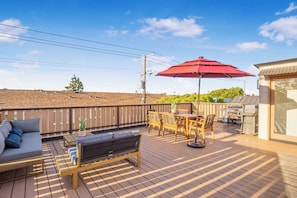 A wooden deck with outdoor furniture, a barbecue grill, and a red umbrella. - Cedar Loft Villa (Venice)