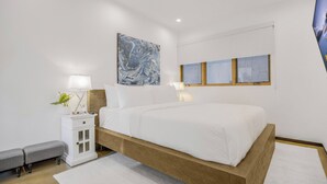 A modern bedroom with a wooden bed frame, white bedding, a nightstand with a lamp, and a wall-mounted artwork. - Cedar Loft Villa (Venice)