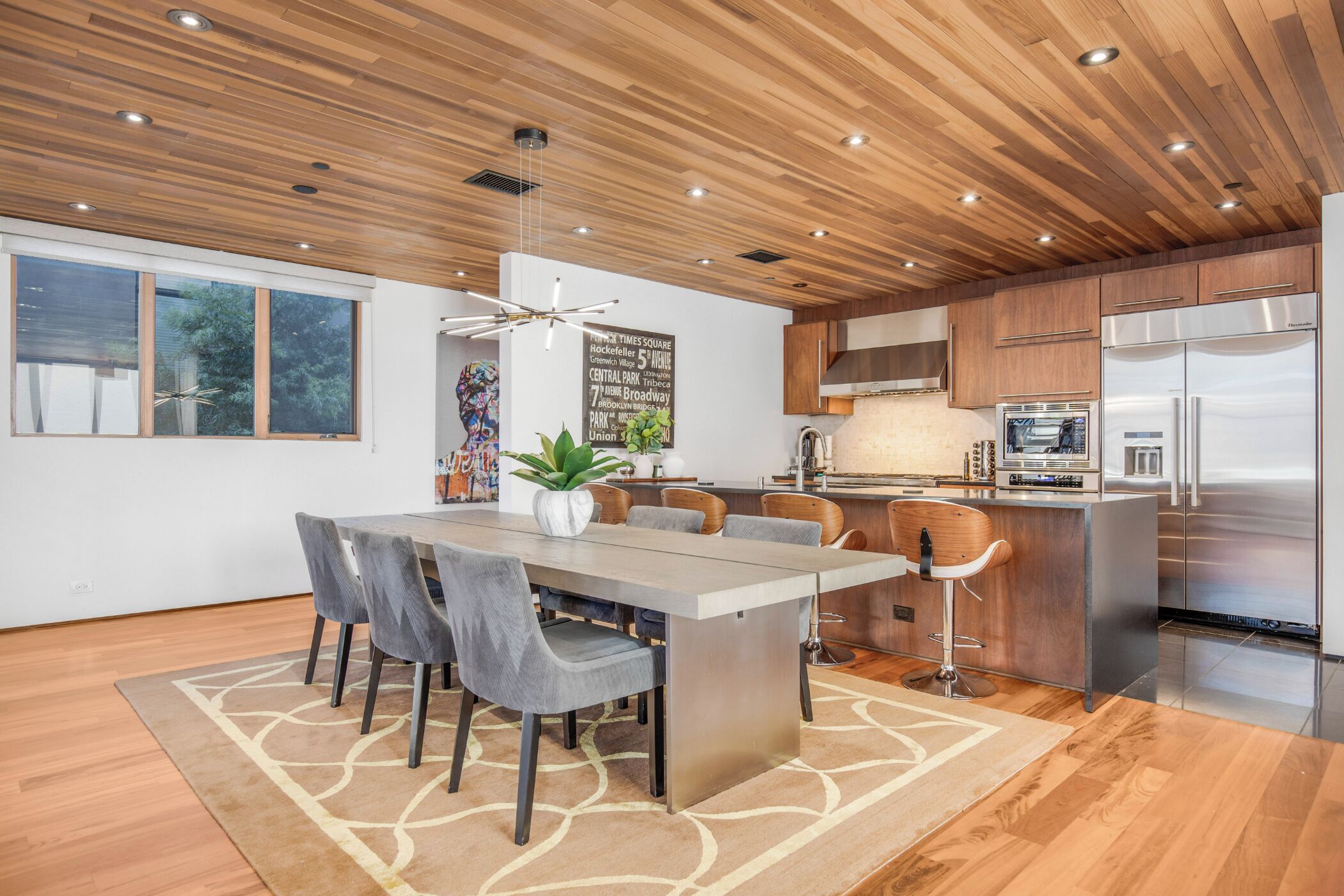 A modern kitchen with wooden ceiling, stainless steel appliances, and a central island.