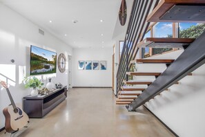 A modern interior with a staircase, a flat-screen TV, and artwork on the walls. - Cedar Loft Villa (Venice)