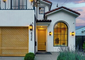 A two-story house with a garage, a large arched window, and a door with a number plaque.