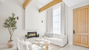 A modern living room with a white sofa, a coffee table, and a fireplace. - Villa Camellia (Studio City)