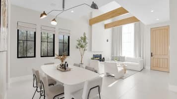 A modern living room with a white sofa, a dining table with chairs, and a fireplace.