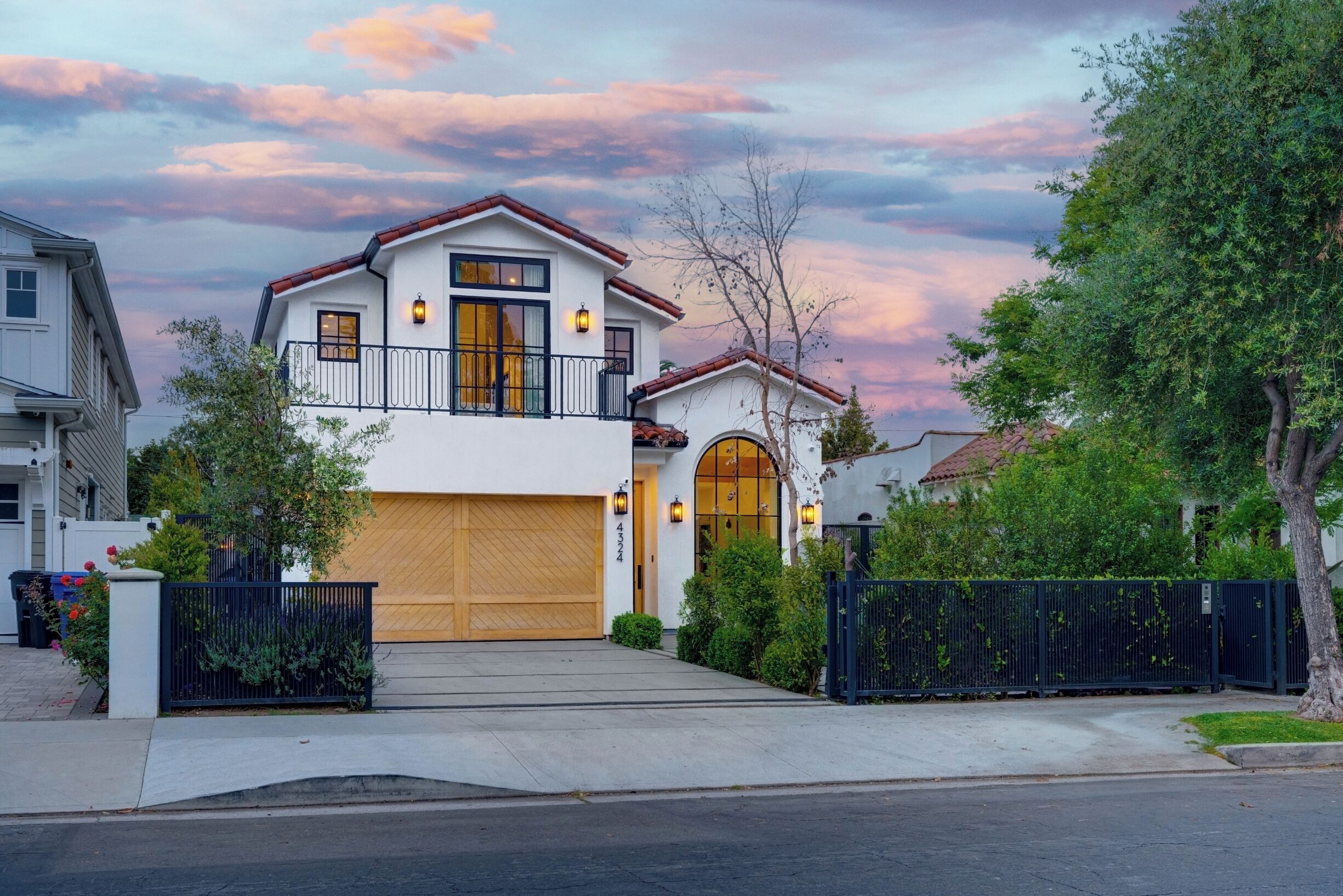A two-story house with a garage, a balcony, and a large arched window.