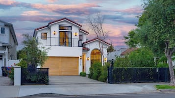A two-story house with a garage, a balcony, and a large arched window.
