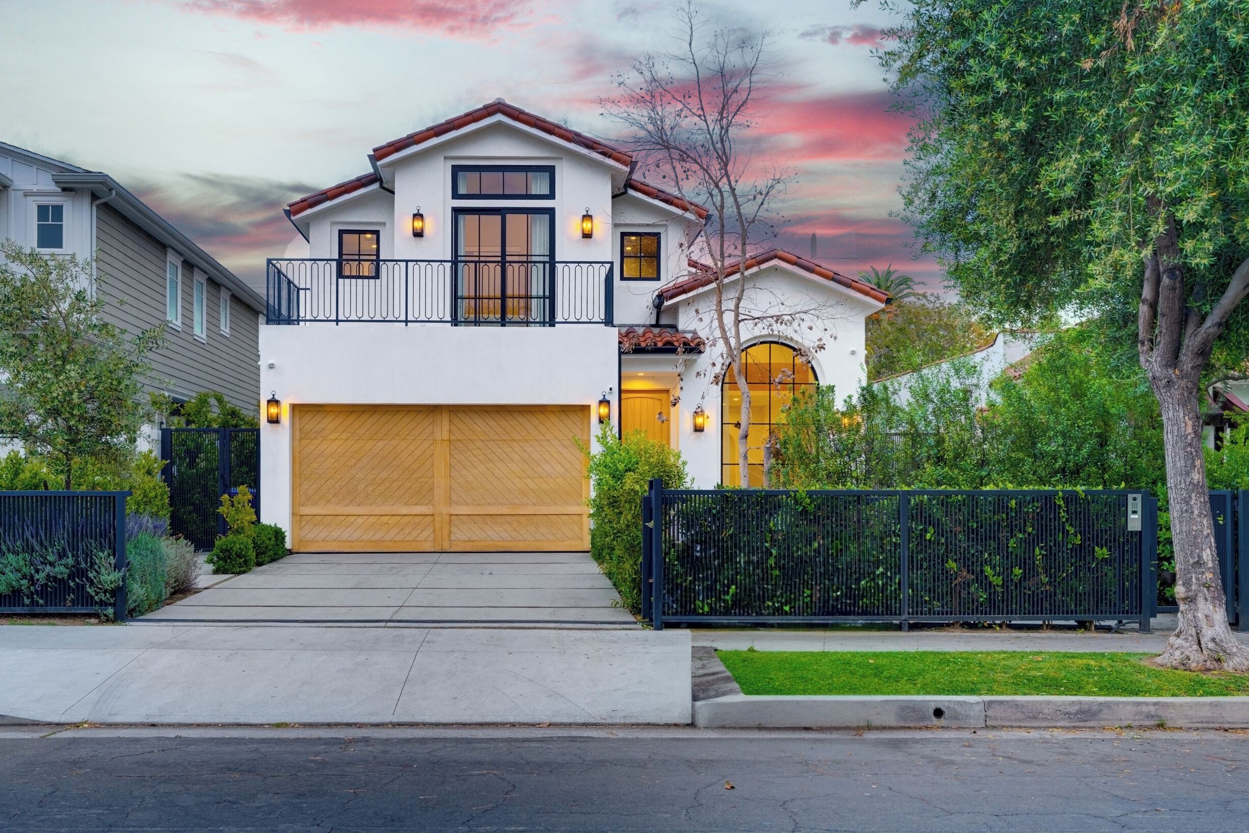 A two-story house with a garage, a balcony, and a black fence.