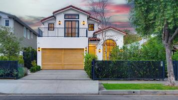A two-story house with a garage, a balcony, and a black fence.