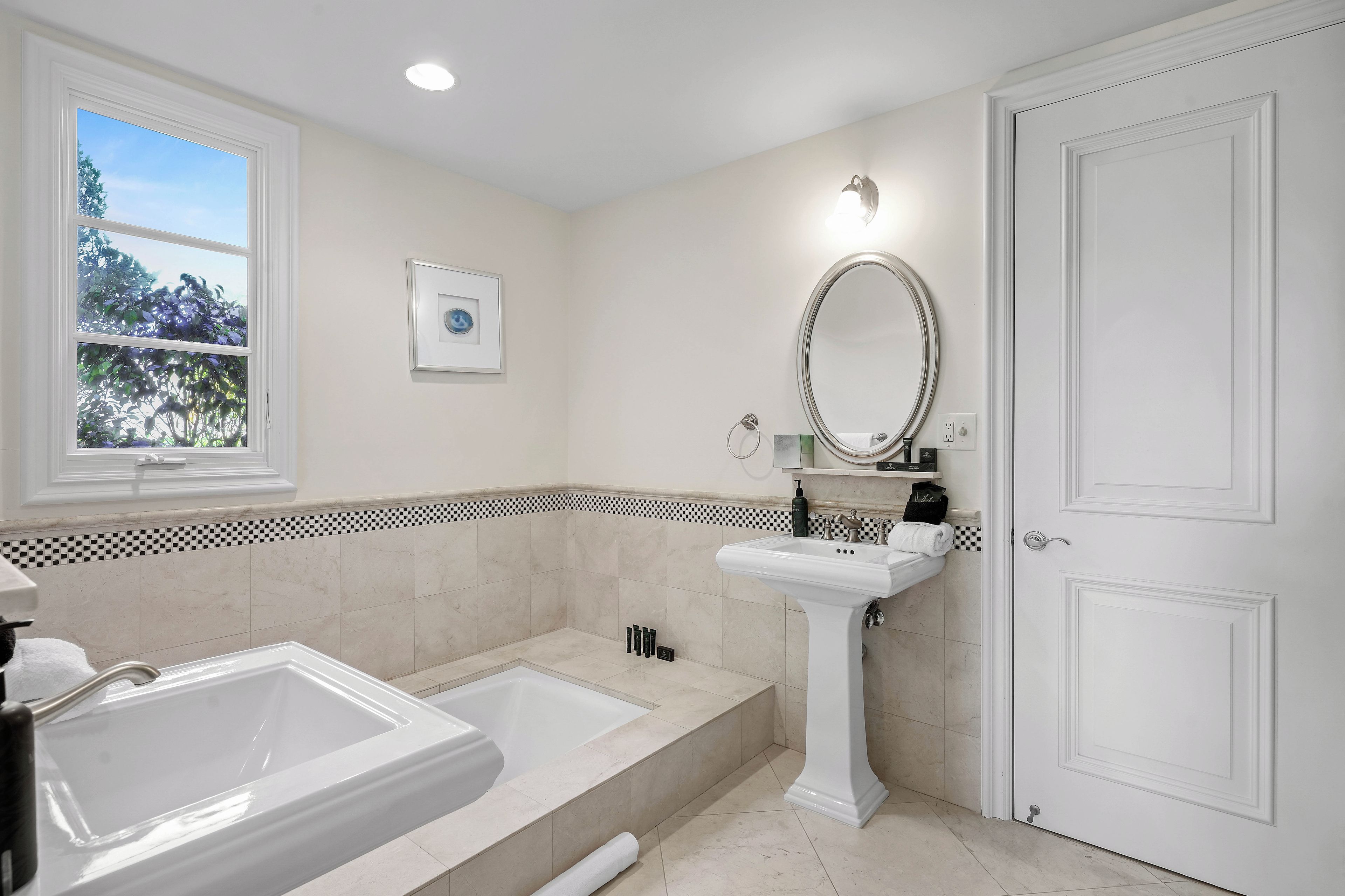 Un baño con una bañera, un lavamanos y un espejo.