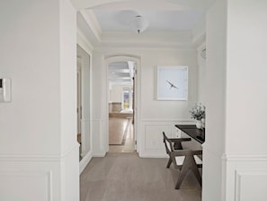 A hallway with a dining area featuring a table and chairs, a ceiling light, and a framed picture on the wall. - Savona Sanctuary Estate (Los Angeles)