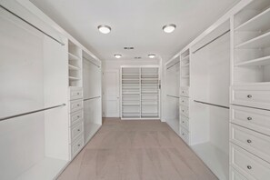 A walk-in closet with white shelving and drawers, a beige carpet, and recessed ceiling lights. - Savona Sanctuary Estate (Los Angeles)