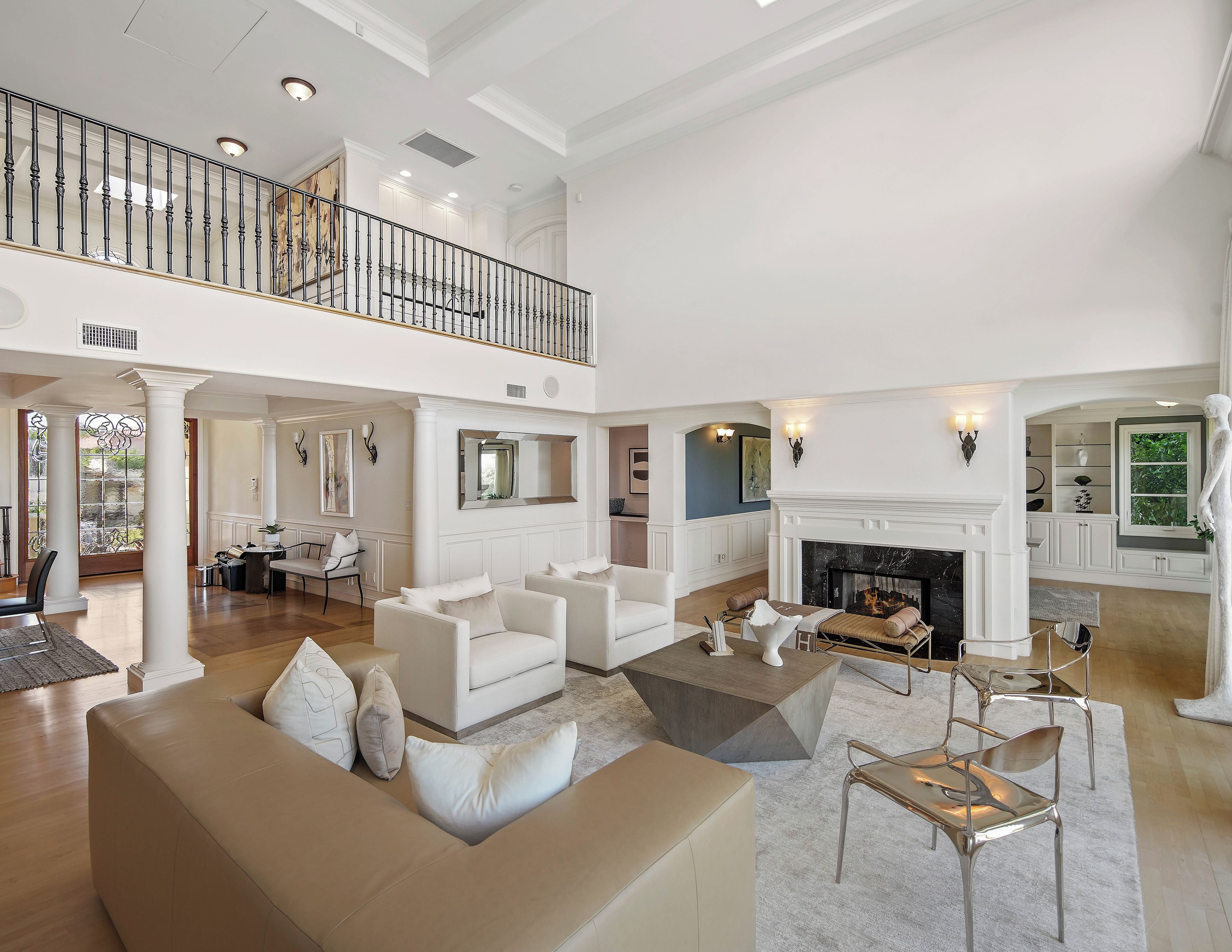 A spacious living area with a high ceiling, a fireplace, and a balcony.