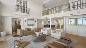 A spacious living area with a high ceiling, a balcony, and a view of the outdoors.