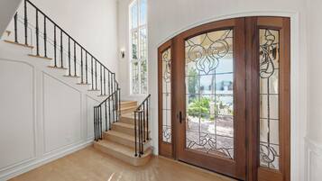 A staircase with black balusters and wooden steps, leading to a door with stained glass panels.